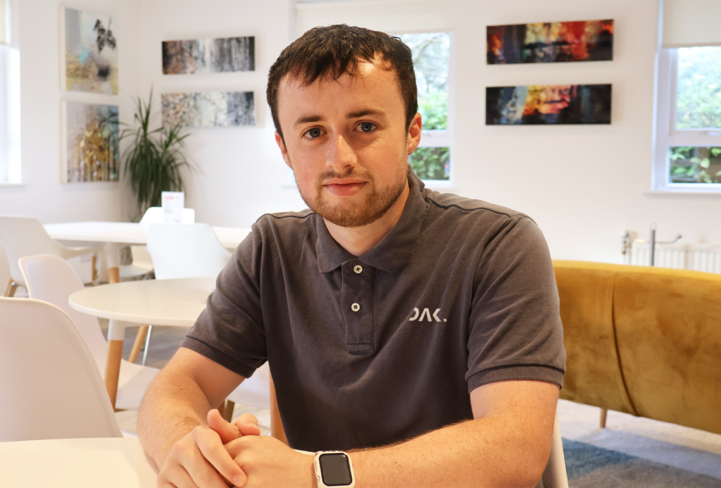 Headshot of the DAK Digital Founder, Ryan Dakin, looking at the camera, with yellow sofas and white chairs and tables behind him.