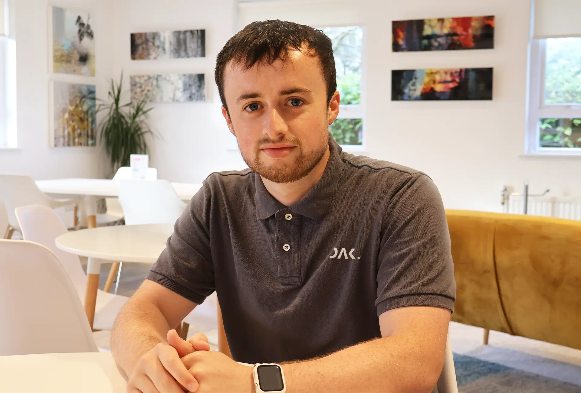 Headshot of the owner of DAK Digital, Ryan Dakin, sat in a vibrant lounge with a branding polo shirt on.